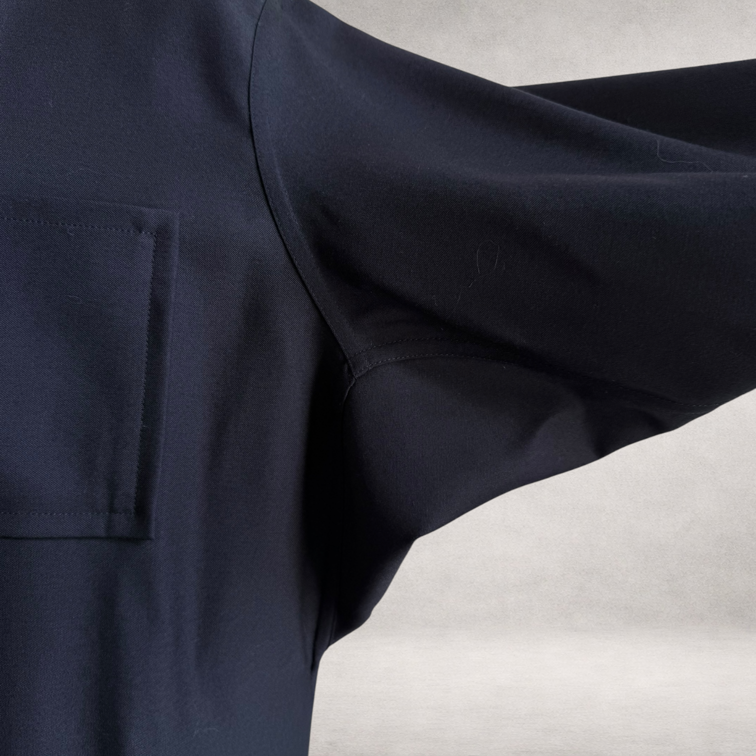 Detail view of the PINTO HERVIA Frame Jacket in black wool showing Aries underarm construction and fluid movement.