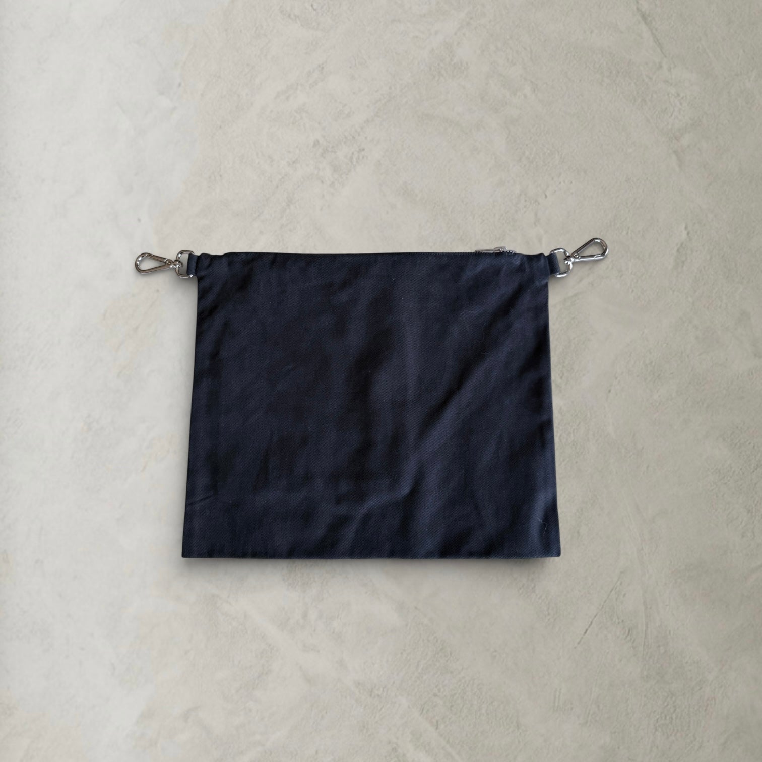 Back view of the PINTO HERVIA Frame Pouch in black cotton drill with detachable silver clip hardware.