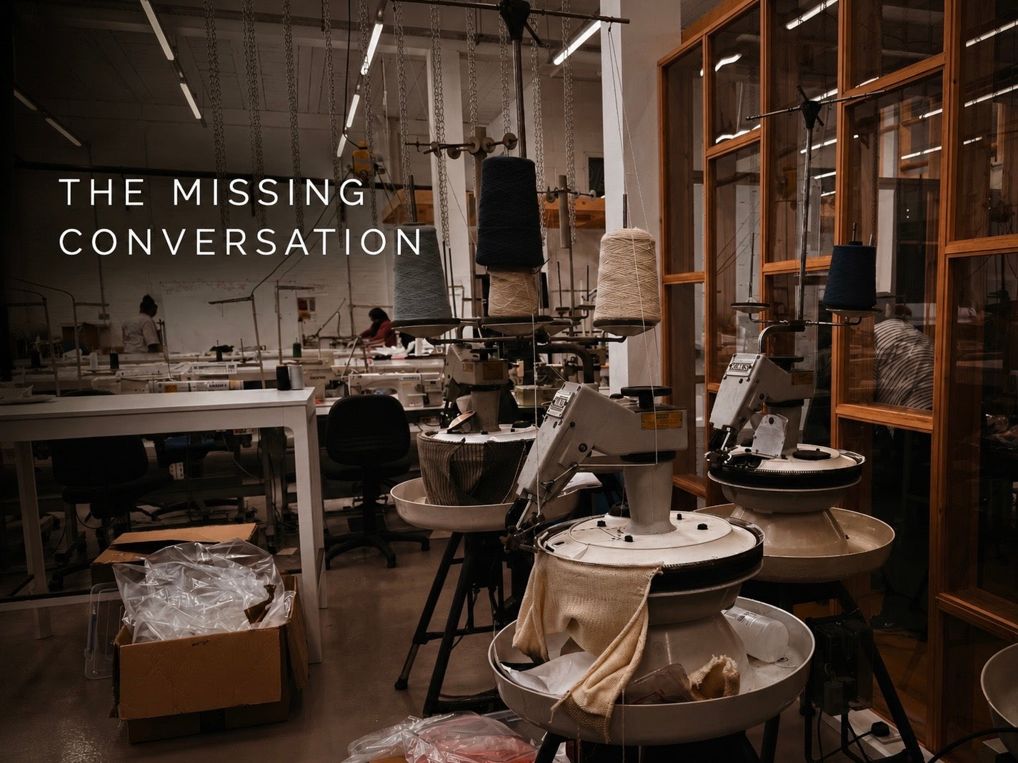 Editorial image of a UK knitwear factory interior with industrial knitting machines, yarn cones and workstations, overlaid with the text “THE MISSING CONVERSATION”.