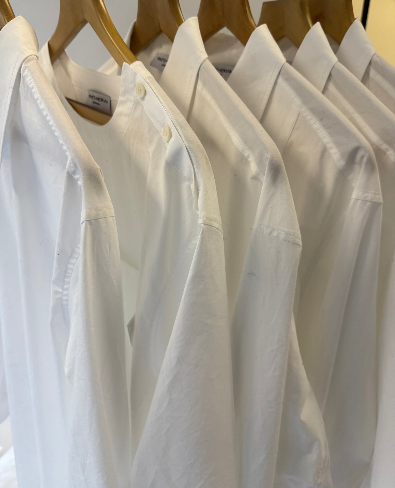 White shirts hanging neatly on a rail.