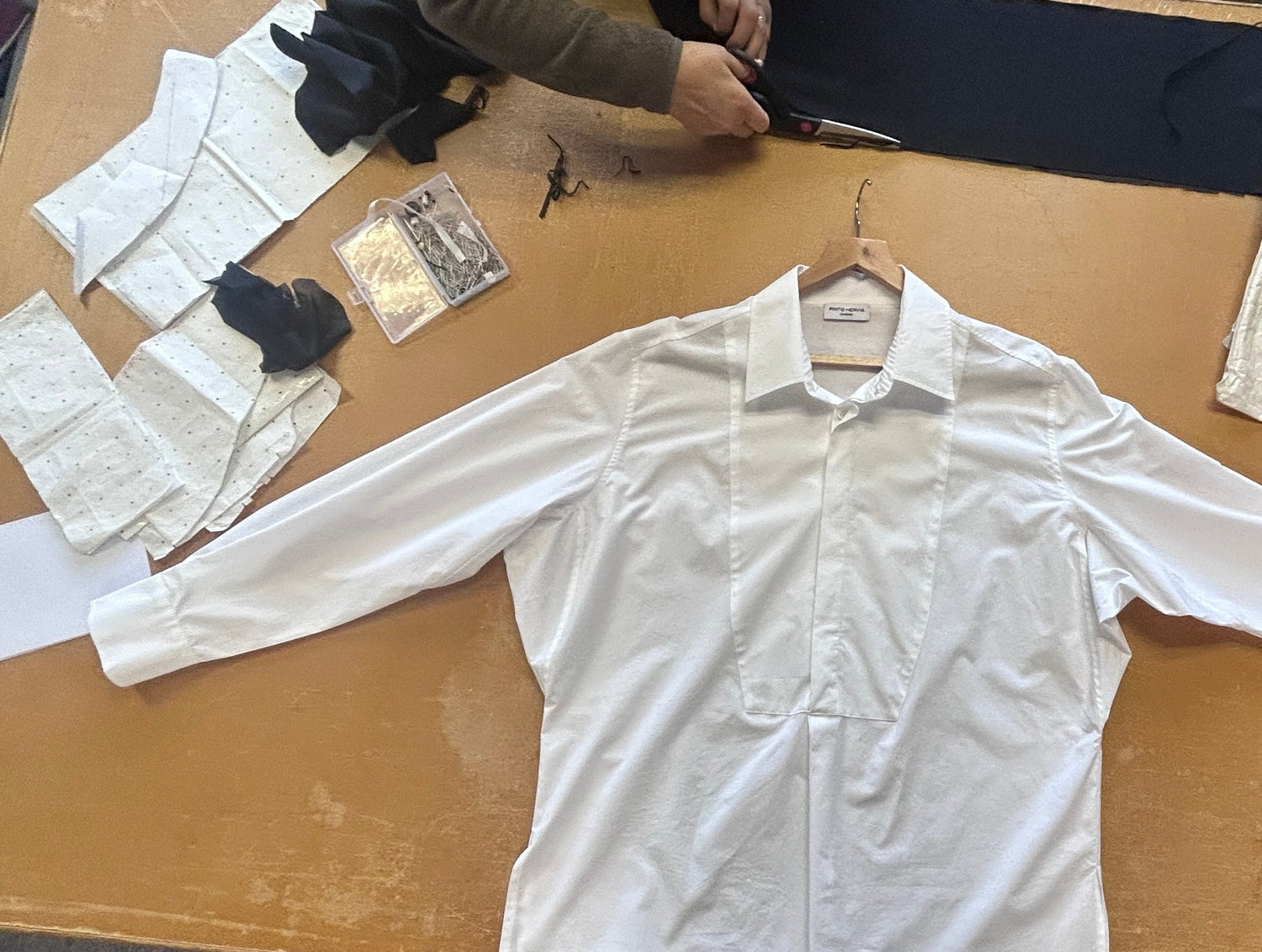 White shirt on a work table with sewing patterns and tools.