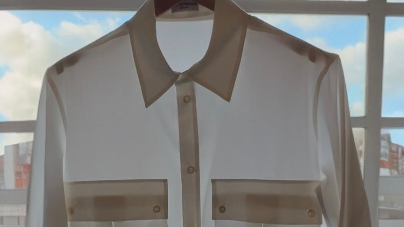 White cotton poplin shirt with contrast collar and chest pockets, hanging on a rail