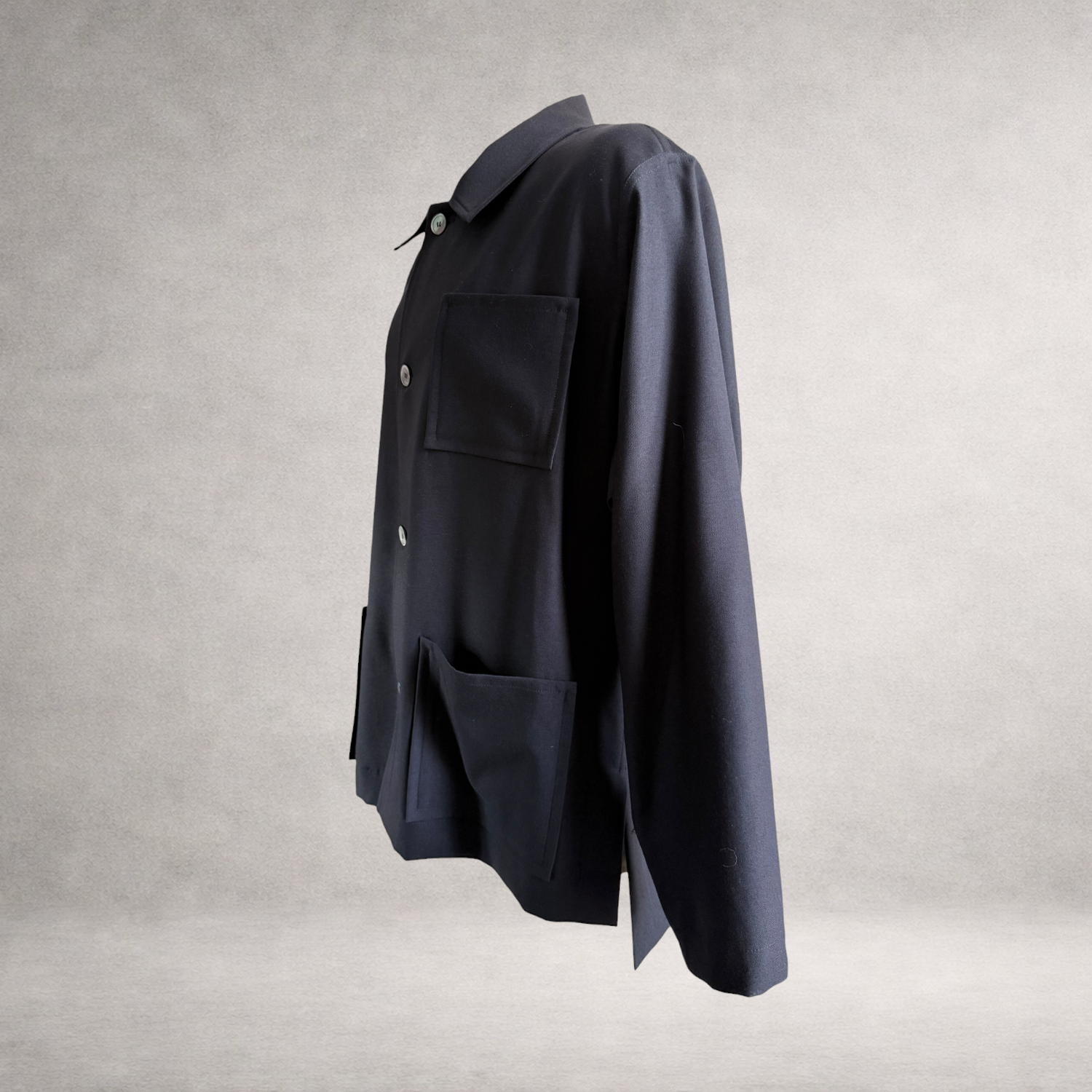 Side view of the PINTO HERVIA Frame Jacket in black wool showing relaxed structure and Aries underarm construction.
