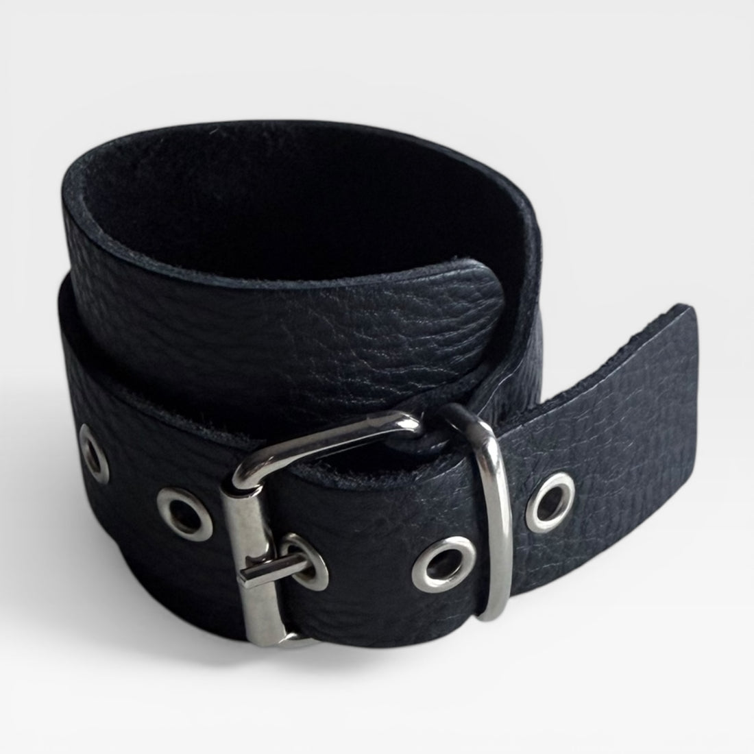Leather cuff bracelet made in England, featuring a curved design and minimal closure, in black with silver buckle.