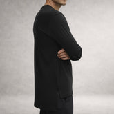Black Atlas long sleeve top in jersey cotton, side view showing extended back length and split hem